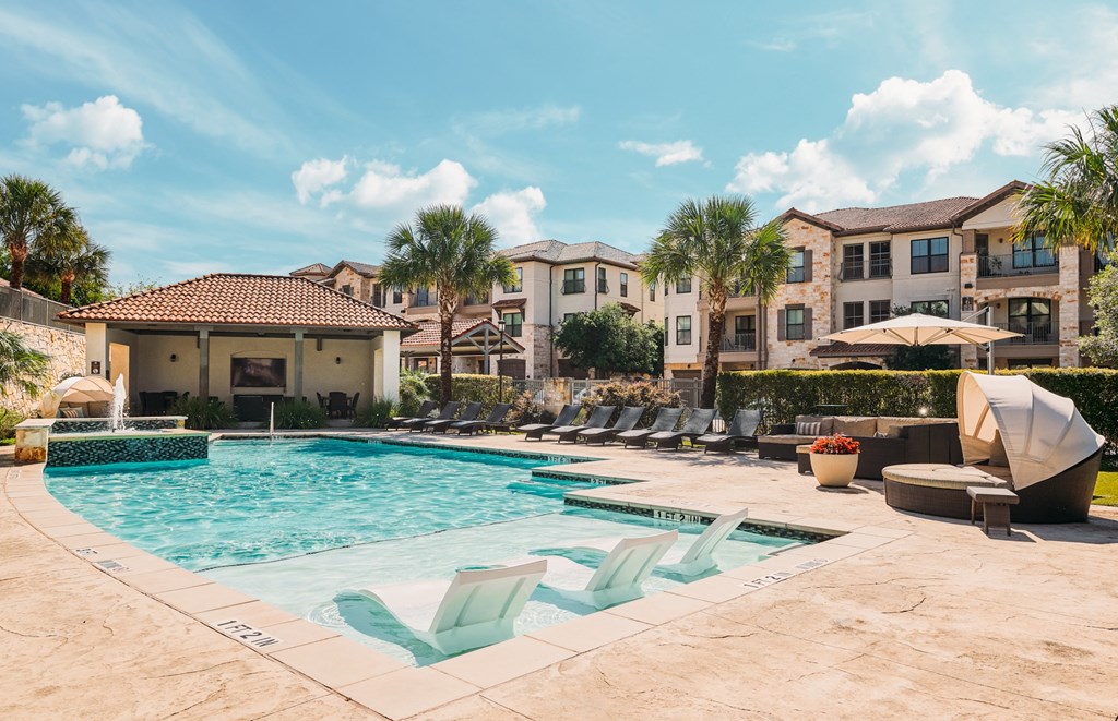 A swimming pool surrounded by lounge chairs and umbrellas.