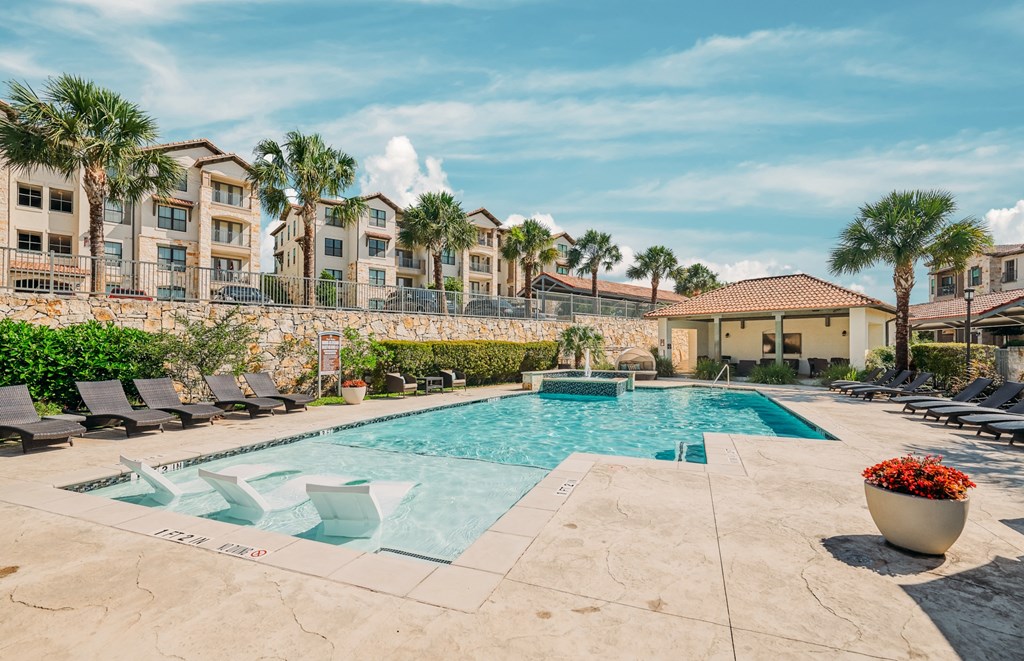 A large swimming pool surrounded by lounge chairs and palm trees.