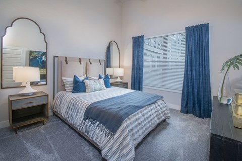 A bedroom with a bed, nightstand, and a mirror.