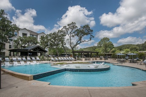 A large outdoor swimming pool with a hot tub and lounge chairs.
