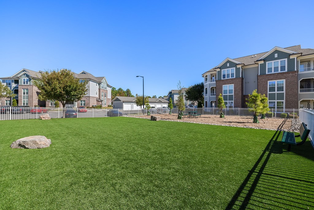A grassy field in front of apartment buildings.