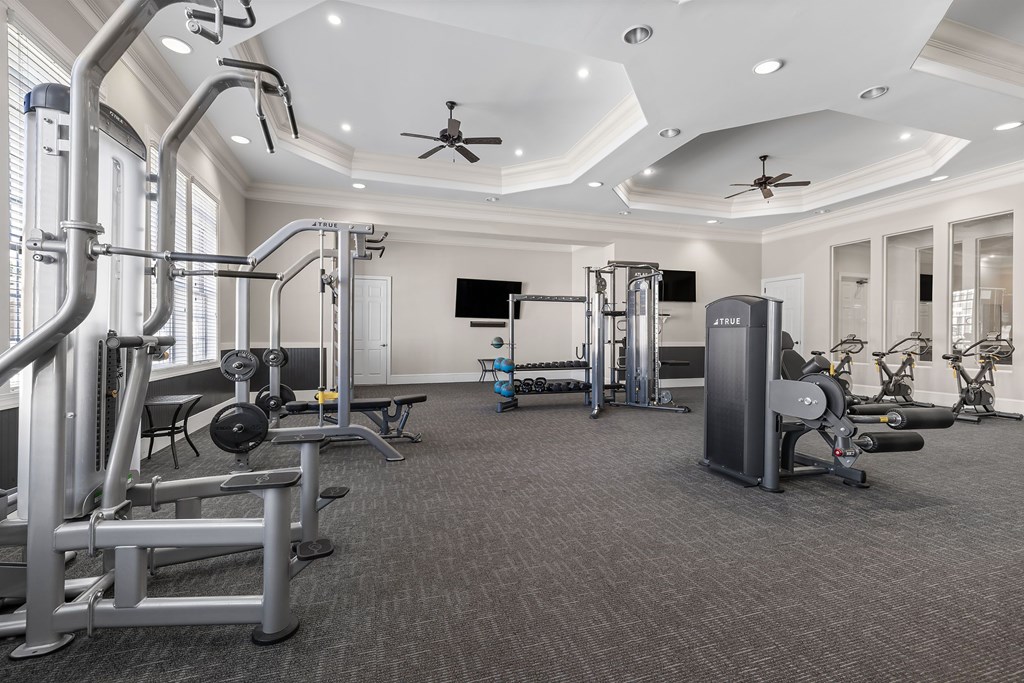 A spacious gym with various exercise equipment and a ceiling fan.