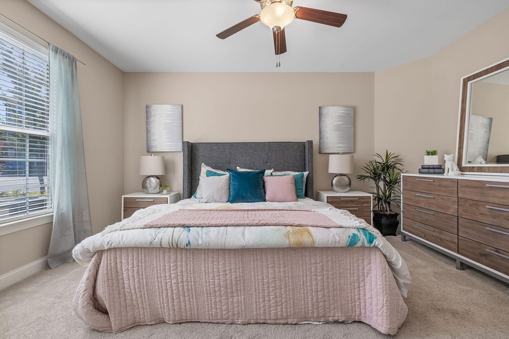 A bedroom with a bed, dresser, and ceiling fan.