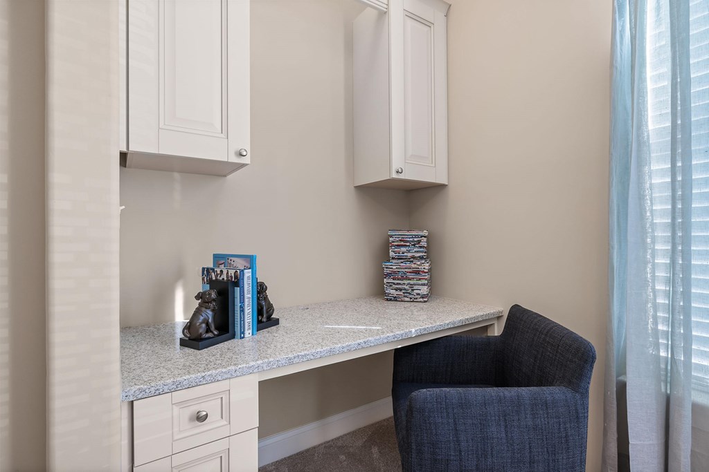 A blue chair sits in front of a desk with a book and a small statue on it.