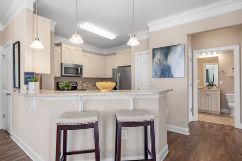 A kitchen with a white counter and bar stools.
