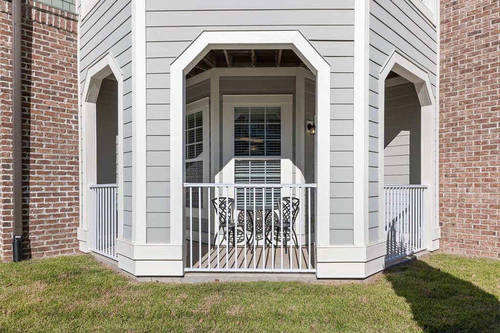 A white house with a grey siding and a white porch.