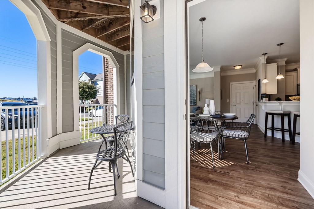 A balcony with a table and chairs overlooks a parking lot.