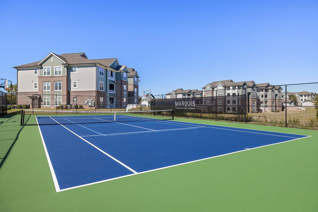 A tennis court in front of apartment buildings.