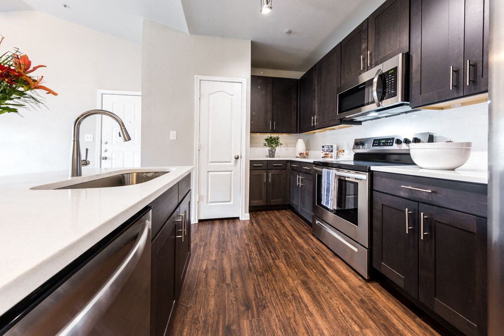A modern kitchen with dark wood cabinets and stainless steel appliances.