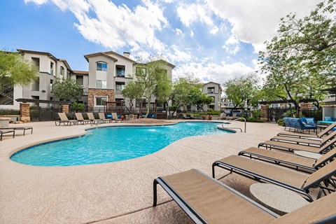 A swimming pool surrounded by lounge chairs and apartment buildings.