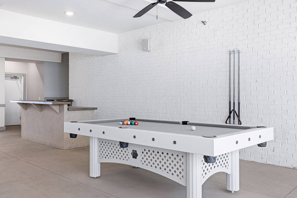 a white pool table in a living room with a white brick wall