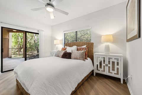 A bedroom with a large bed, a ceiling fan, and a sliding glass door.