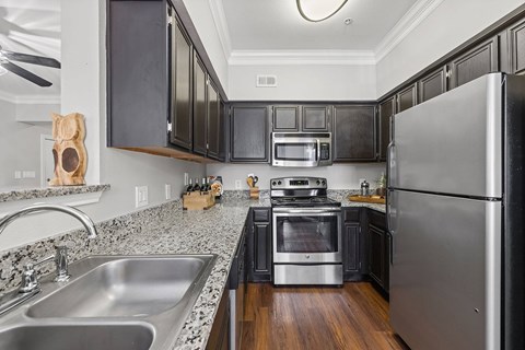A modern kitchen with black cabinets and stainless steel appliances.
