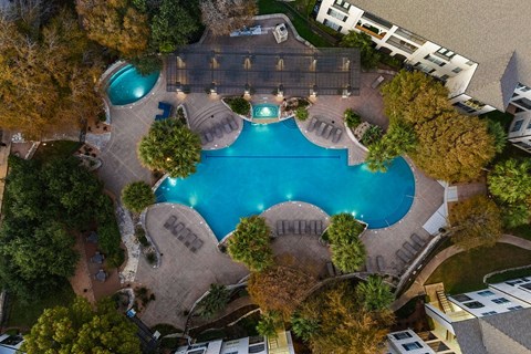 An aerial view of a swimming pool surrounded by trees and buildings.