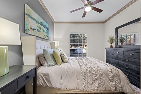 A bedroom with a large bed and a ceiling fan.