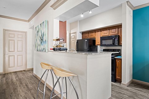 A kitchen with a white counter and bar stools.