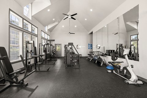 A spacious gym with a variety of equipment and mirrors on the wall.