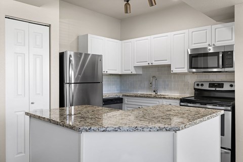 A kitchen with granite countertops and white cabinets.