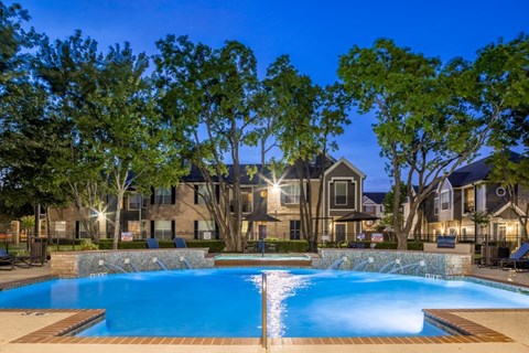 A swimming pool surrounded by trees and a building in the background.