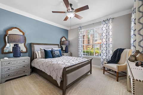 A bedroom with a bed, chair, and a ceiling fan.