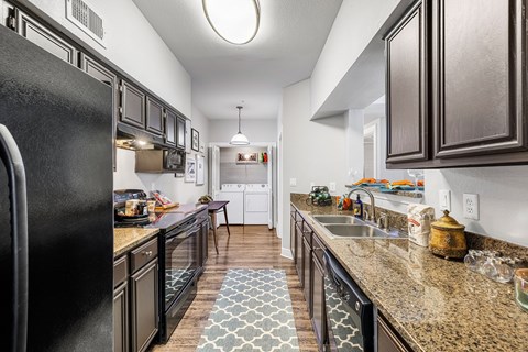 A kitchen with black cabinets and a black refrigerator.