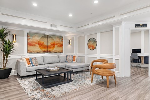 A living room with a grey sofa, a wooden chair, and a painting on the wall.