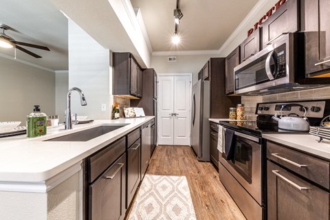 A modern kitchen with dark wood cabinets and stainless steel appliances.