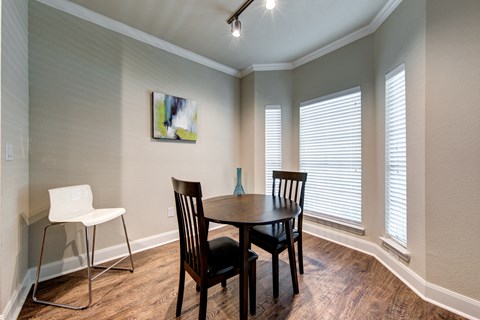 A dining room with a table, chairs and a painting on the wall.