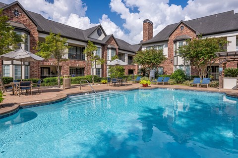 A large swimming pool in front of a brick building.
