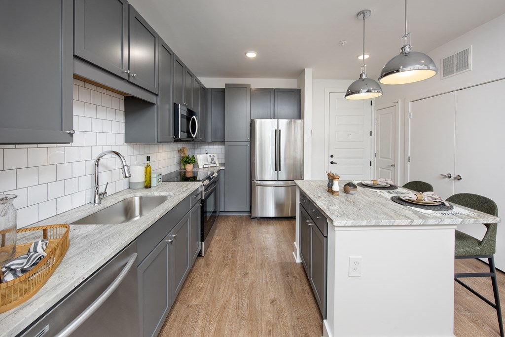 a large kitchen with stainless steel appliances and gray cabinets