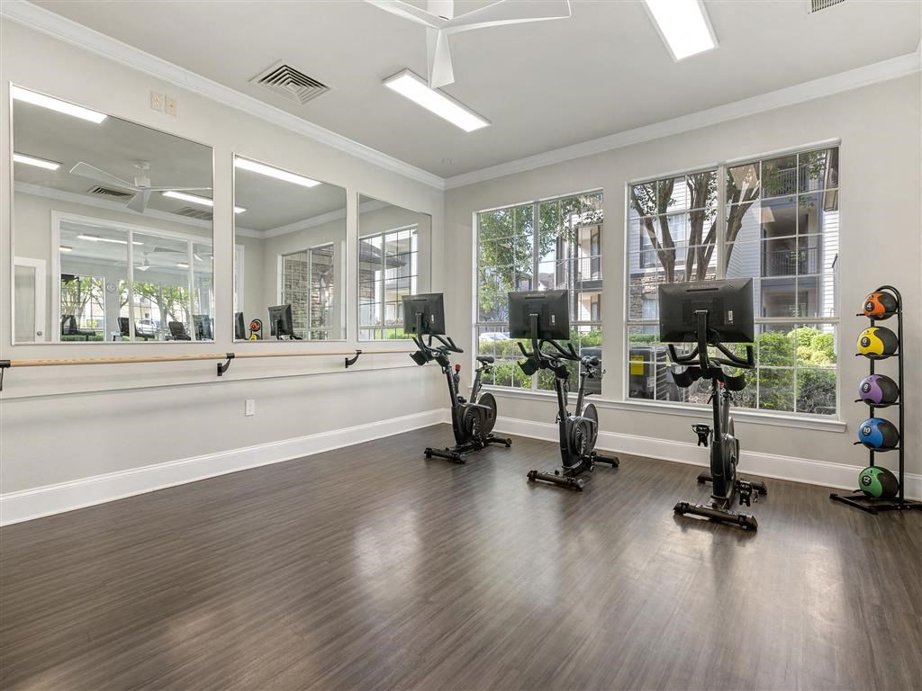 a workout room with weights and mirrors in front of windows