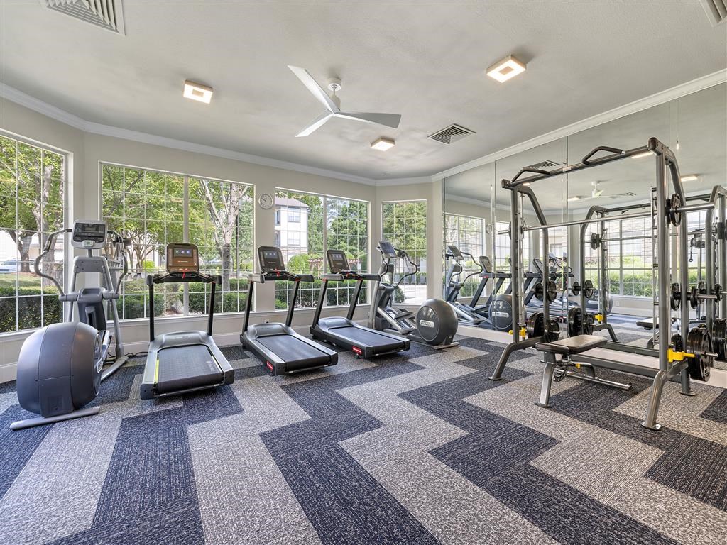 a gym with cardio equipment and windows at the estates apartments