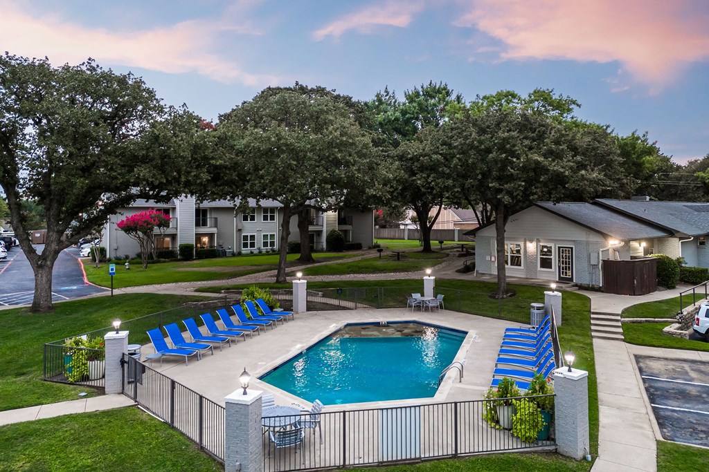 an aerial view of a swimming pool with blue lounge chairs in front of a house