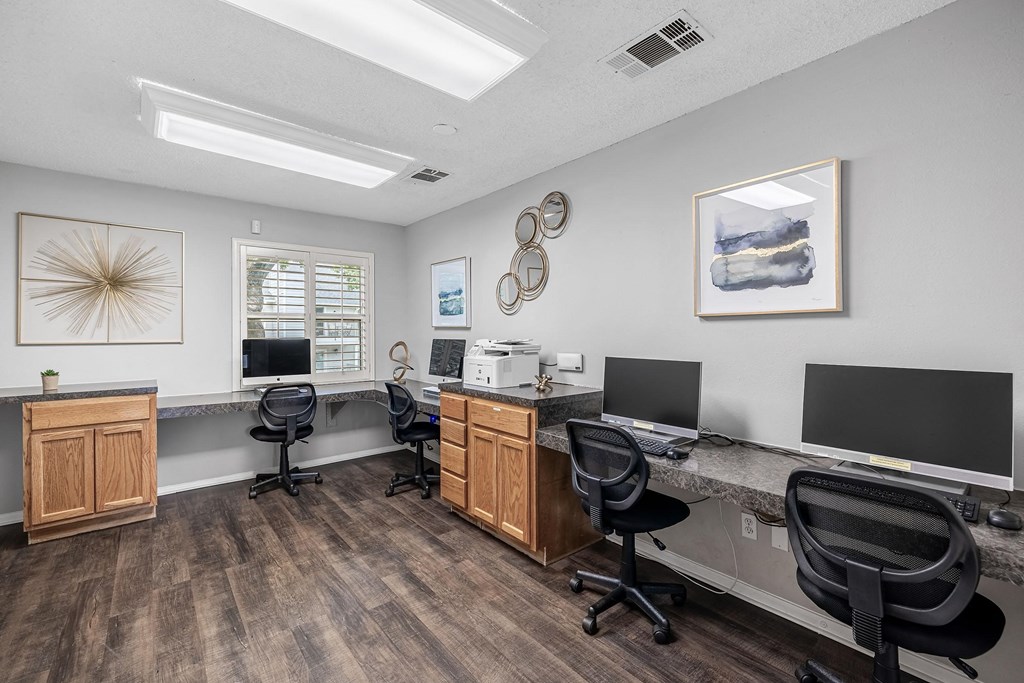 two computers and three monitors on desks in a room with chairs
