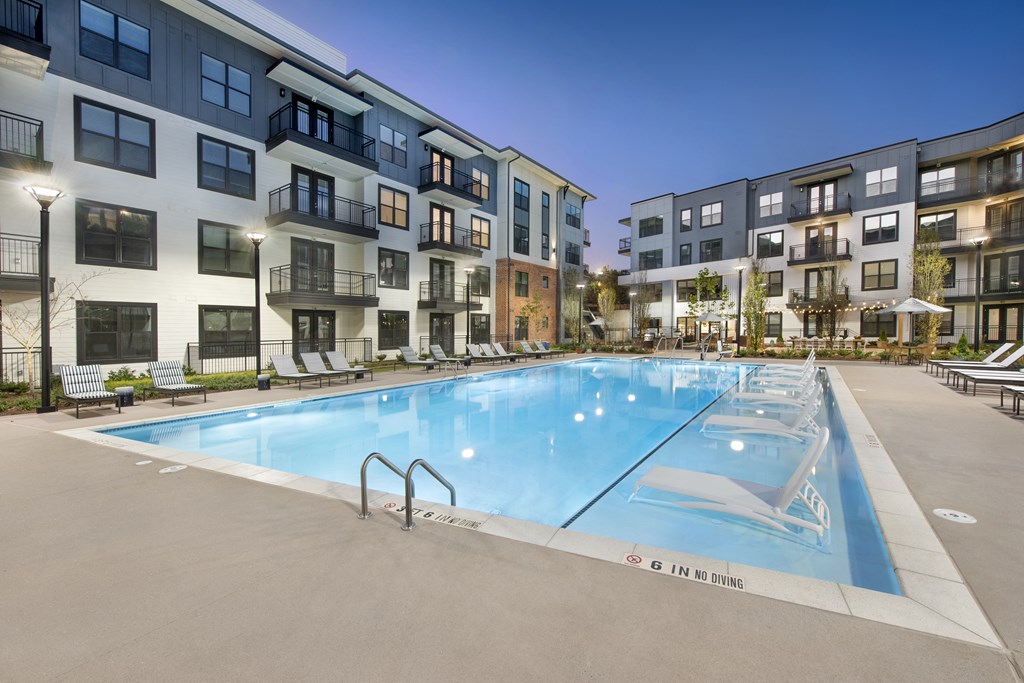 an apartment pool with an apartment building in the background
