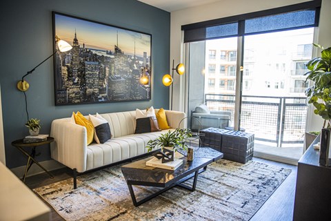 A living room with a white couch and a large cityscape painting on the wall.