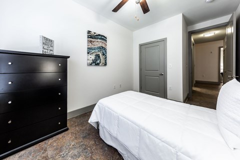 A bedroom with a white bed and a black dresser.