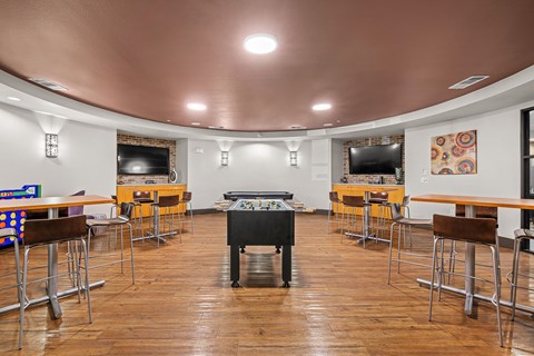 A room with a pool table and bar stools.
