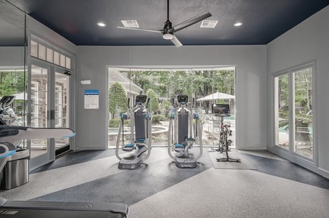A gym with treadmills, elliptical machines, and a fan.