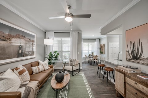 A living room with a brown couch and a ceiling fan.