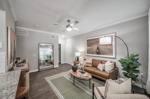 A living room with a brown couch, a coffee table, and a large painting on the wall.