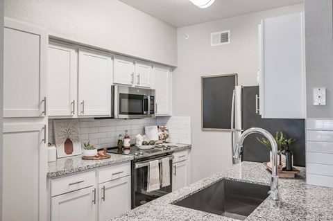 A kitchen with white cabinets stainless steel appliances