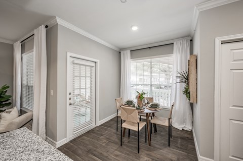 A dining room with a table set for two and a view of the outside.
