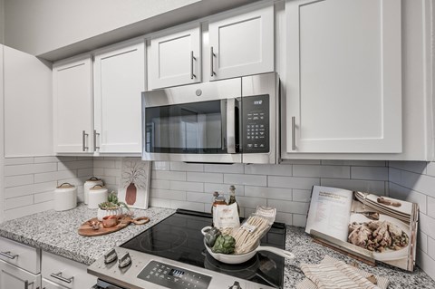 A modern kitchen with a stove top oven and microwave above it.