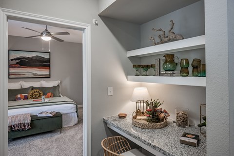 A bedroom with a bed, a chair, and a shelf with decorative items.