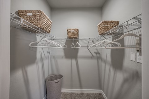 A white closet with three shelves and baskets on them.