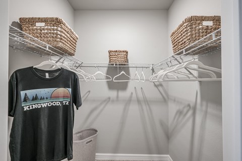 A black t-shirt with "Kingwood, TX" printed on it is displayed on a clothes rack.