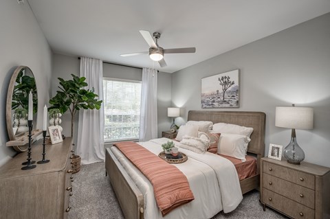 A bedroom with a large bed, a dresser, and a ceiling fan.