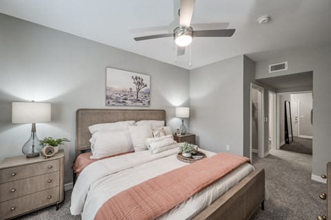 A bedroom with a bed, nightstand, and a painting on the wall.