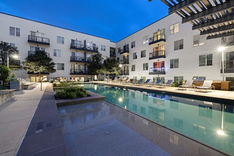 A modern apartment complex with a pool and a walkway.